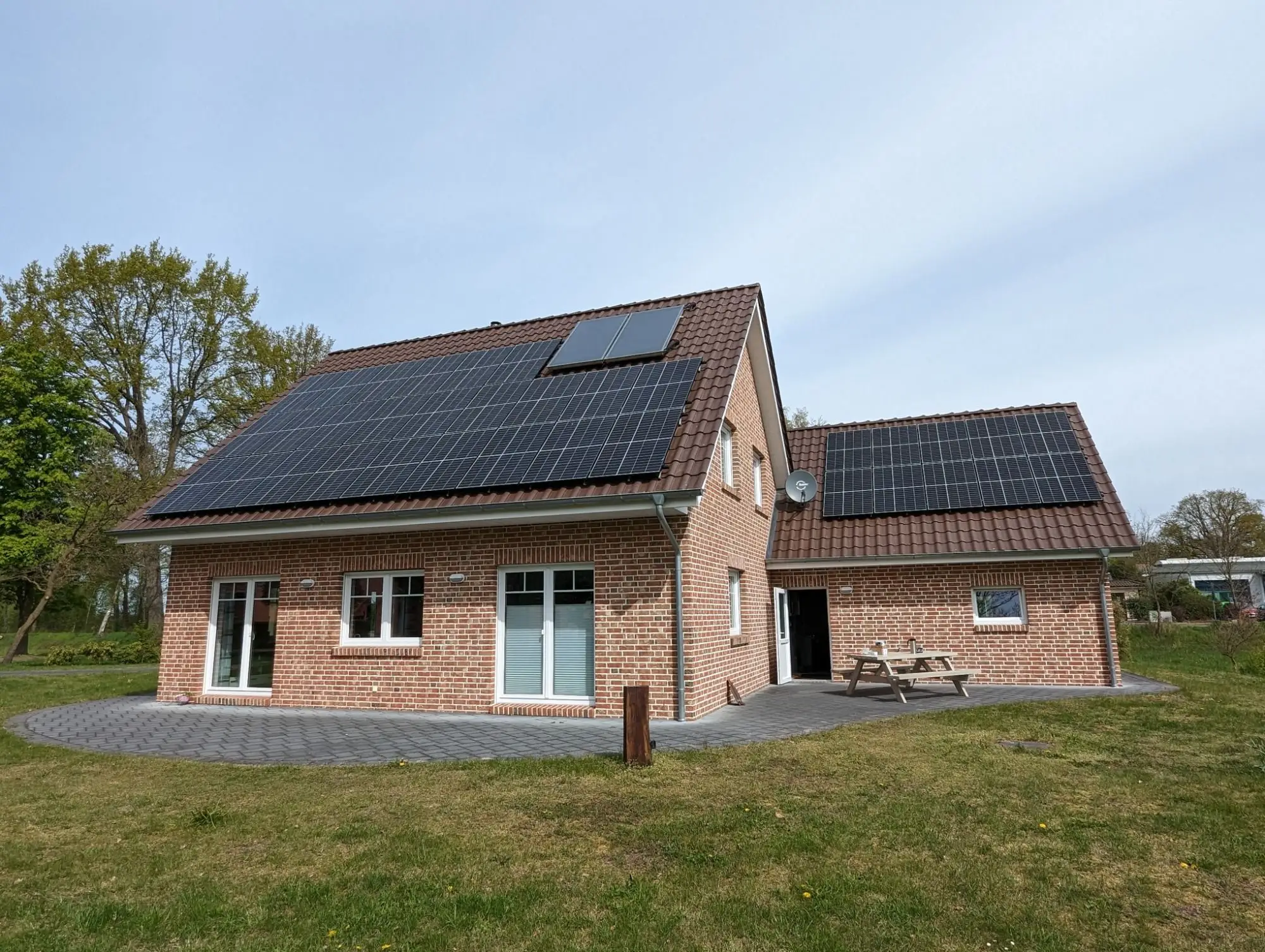 Einfamilienhaus mit Klinkerfassade, dessen Dach und Garagendach vollflächig mit Photovoltaikmodulen belegt sind