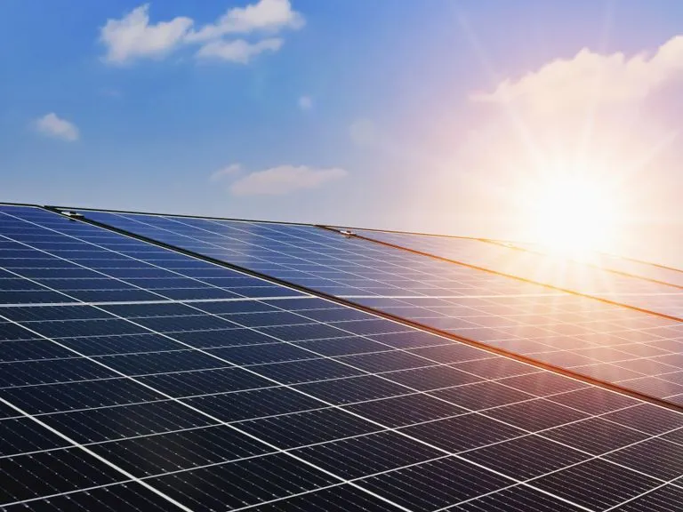 Photovoltaikmodule in Nahaufnahme vor blauem Himmel mit tief stehender Sonne